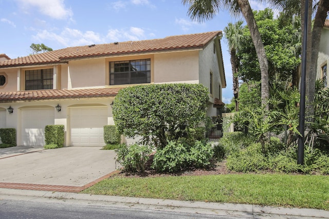 mediterranean / spanish home with driveway, a tiled roof, a garage, and stucco siding