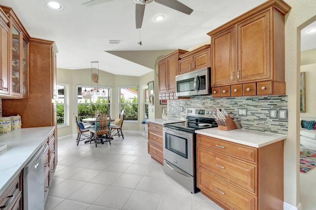 kitchen with appliances with stainless steel finishes, brown cabinetry, visible vents, and tasteful backsplash