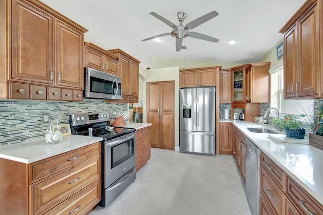 kitchen with brown cabinets, vaulted ceiling, stainless steel appliances, and a sink