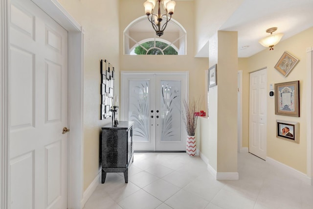 entryway with light tile patterned floors, french doors, baseboards, and an inviting chandelier