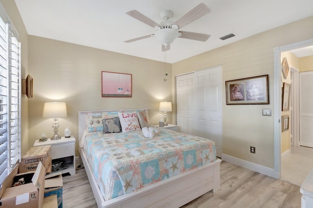 bedroom with light wood finished floors, a closet, visible vents, ceiling fan, and baseboards