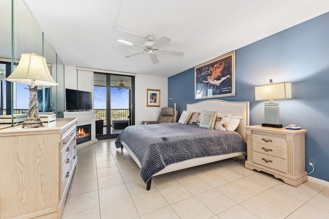 bedroom with light tile patterned floors, a warm lit fireplace, baseboards, access to exterior, and floor to ceiling windows