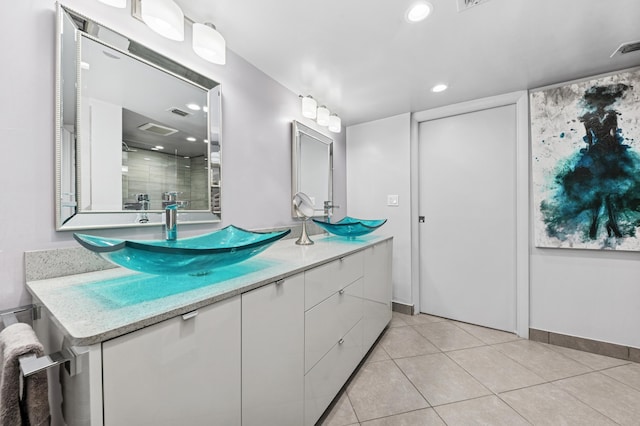 full bathroom with double vanity, a stall shower, tile patterned flooring, and a sink