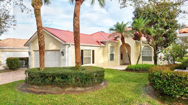 view of front facade with metal roof, an attached garage, decorative driveway, stucco siding, and a standing seam roof