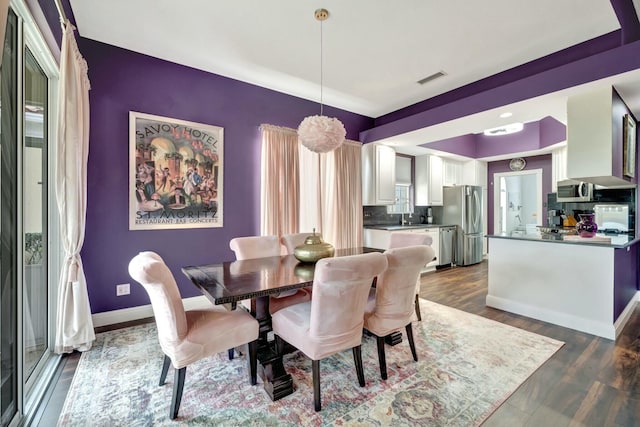 dining room with dark wood-style floors, visible vents, and baseboards