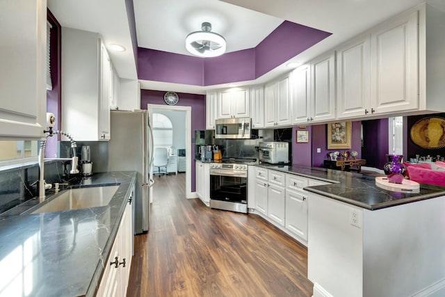 kitchen with stainless steel appliances, dark wood-type flooring, white cabinetry, and tasteful backsplash