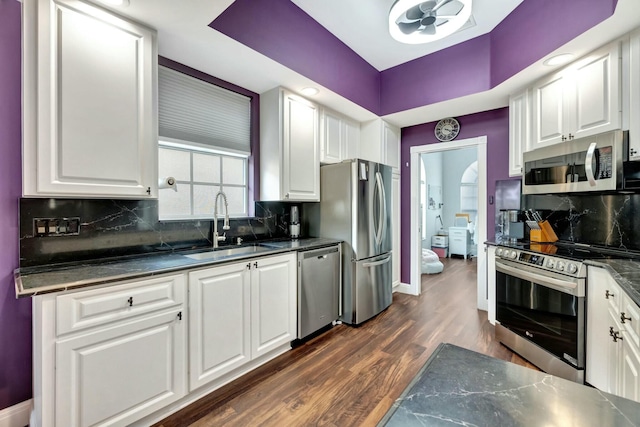 kitchen with stainless steel appliances, dark wood-style flooring, white cabinets, and a sink