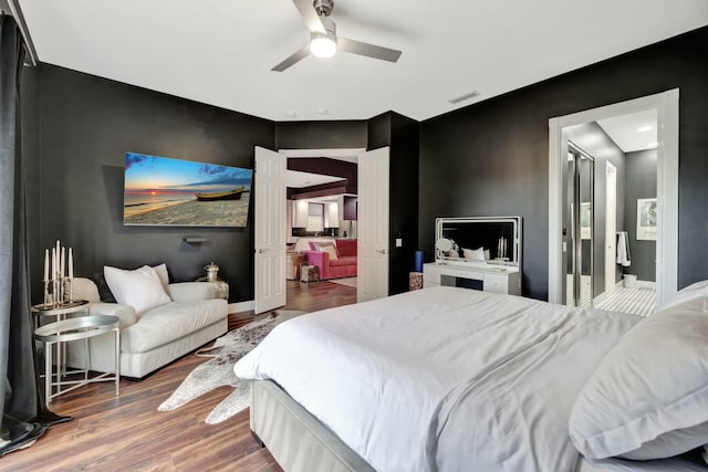 bedroom featuring a ceiling fan, wood finished floors, visible vents, and baseboards