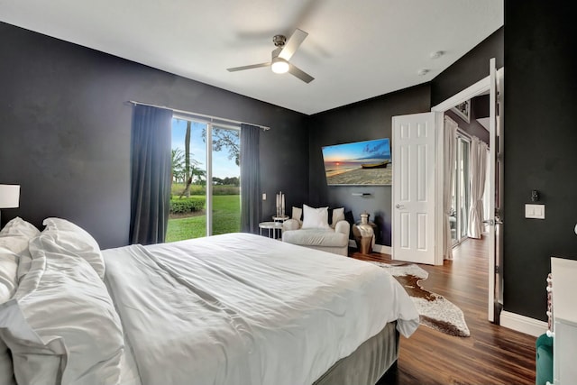 bedroom featuring an accent wall, dark wood-type flooring, a ceiling fan, and baseboards