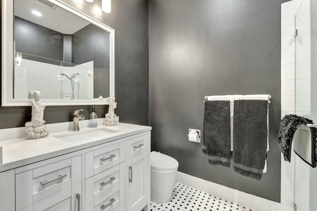 full bath with toilet, visible vents, vanity, baseboards, and tiled shower