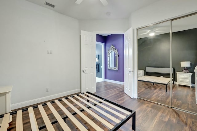 bedroom with baseboards, visible vents, ceiling fan, wood finished floors, and a closet