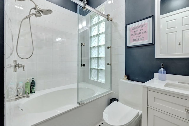 bathroom featuring toilet, combined bath / shower with glass door, and vanity