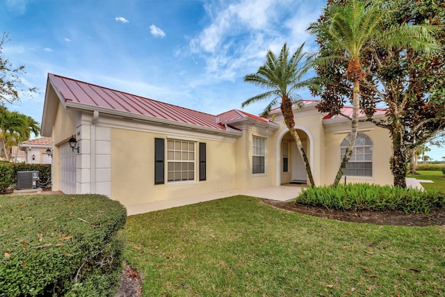 mediterranean / spanish home with a front yard, a standing seam roof, an attached garage, and stucco siding