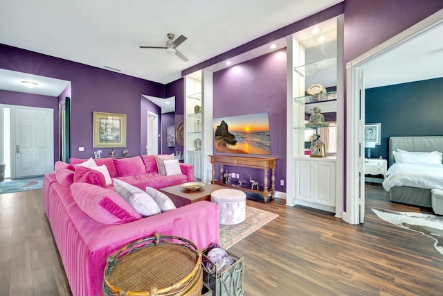 living room featuring wood finished floors, visible vents, baseboards, a ceiling fan, and built in features