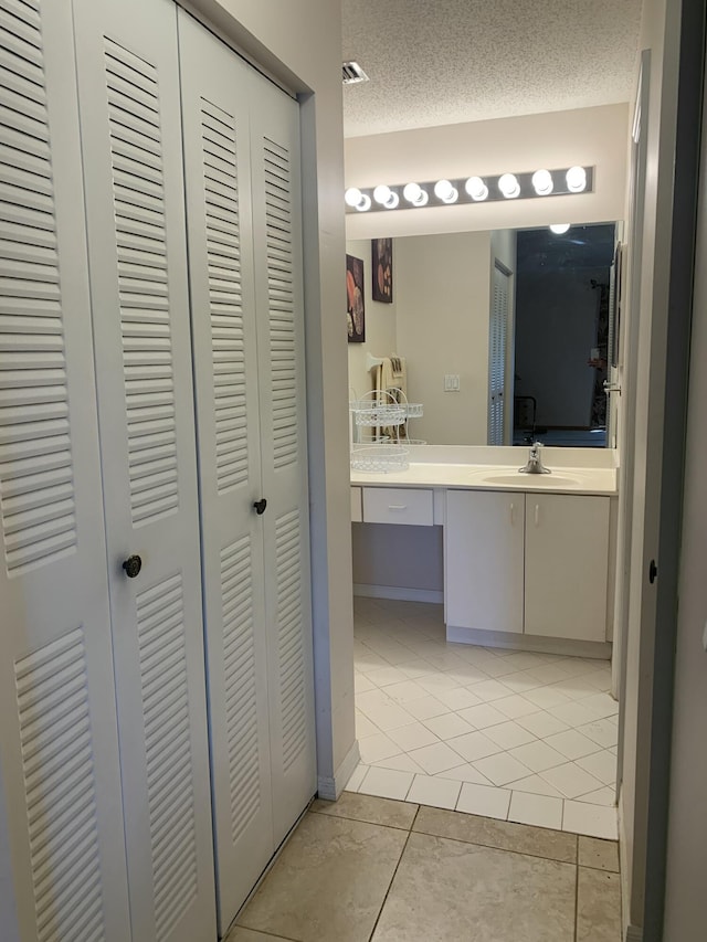 bathroom with a textured ceiling, visible vents, vanity, a closet, and tile patterned floors