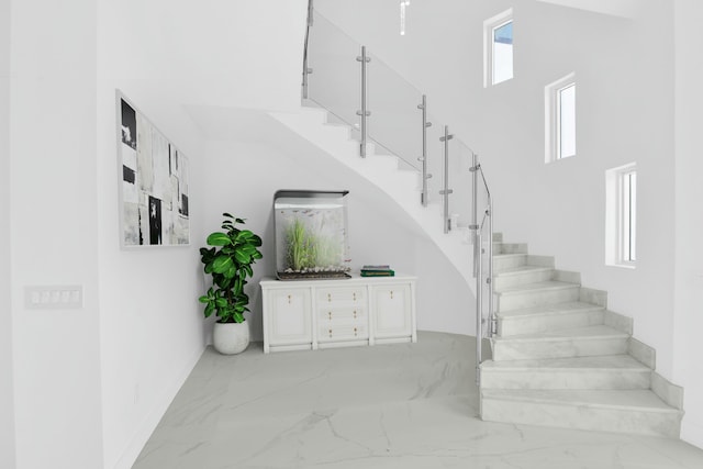 stairway with marble finish floor, a high ceiling, and plenty of natural light