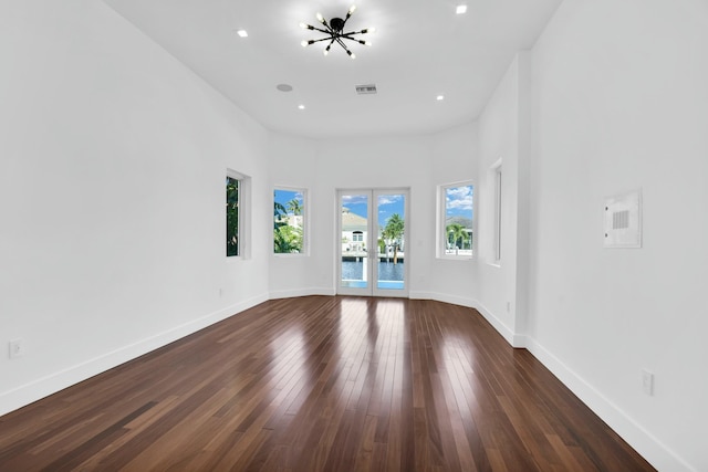 unfurnished living room with french doors, visible vents, dark wood finished floors, and baseboards