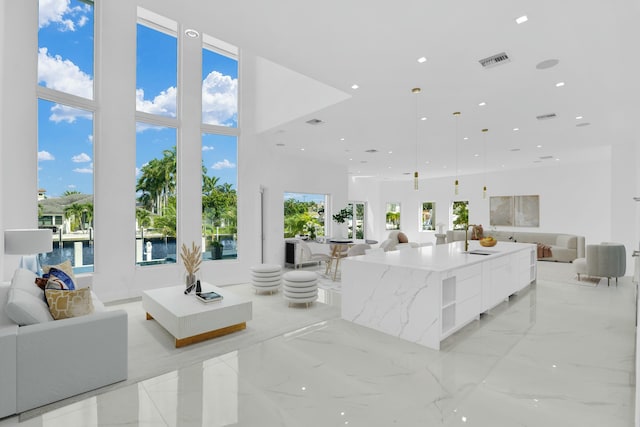 living room featuring recessed lighting, marble finish floor, visible vents, and a high ceiling