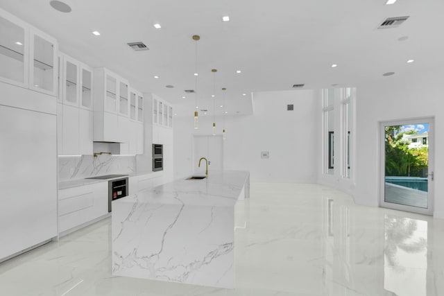 kitchen featuring marble finish floor, visible vents, white cabinets, modern cabinets, and a large island with sink