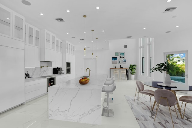 kitchen with visible vents, white cabinetry, marble finish floor, modern cabinets, and a large island with sink