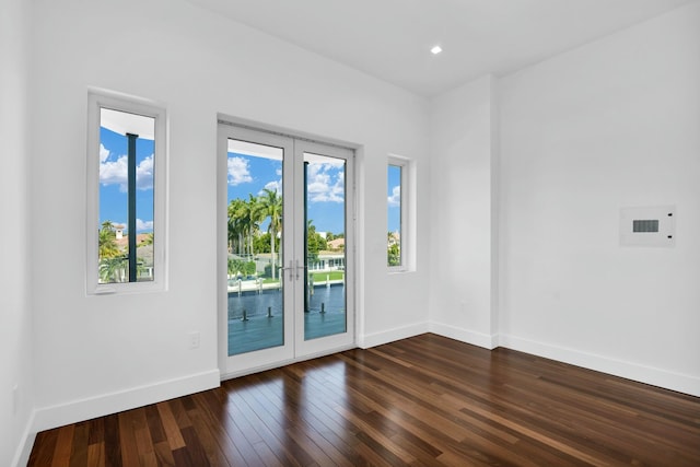 empty room featuring baseboards, dark wood finished floors, and french doors