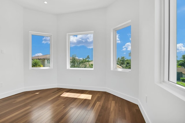 spare room featuring dark wood-style floors and baseboards