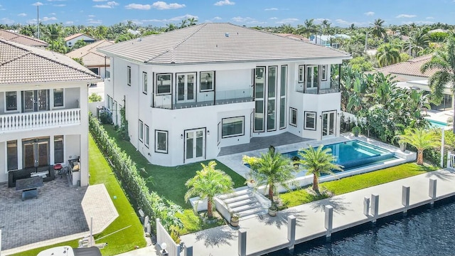 rear view of property featuring stucco siding, a lawn, a patio area, a fenced backyard, and an outdoor pool