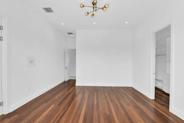 unfurnished room with visible vents, a notable chandelier, baseboards, and wood finished floors