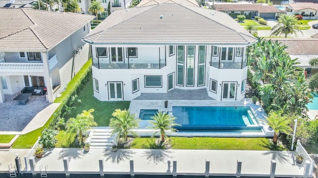 back of house featuring a patio, an outdoor pool, a residential view, and stucco siding