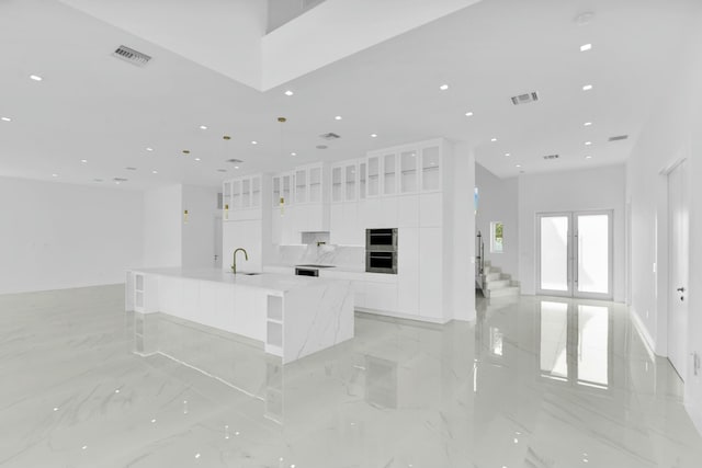 kitchen with a sink, visible vents, white cabinets, marble finish floor, and modern cabinets