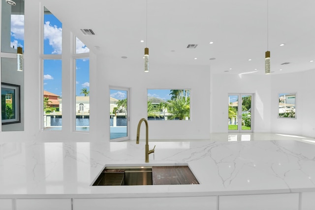 kitchen with light stone countertops, visible vents, open floor plan, and a sink