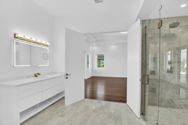 bathroom with baseboards, vanity, a marble finish shower, and wood finished floors