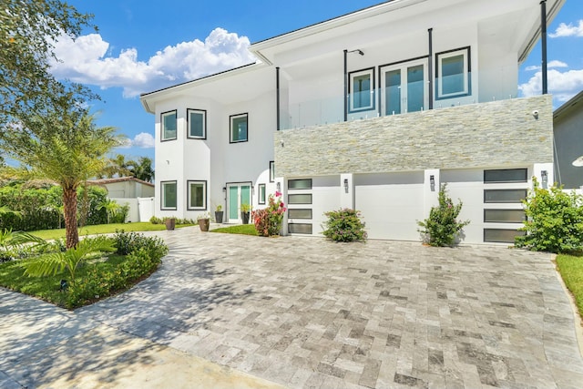 view of front facade with stone siding, decorative driveway, and stucco siding