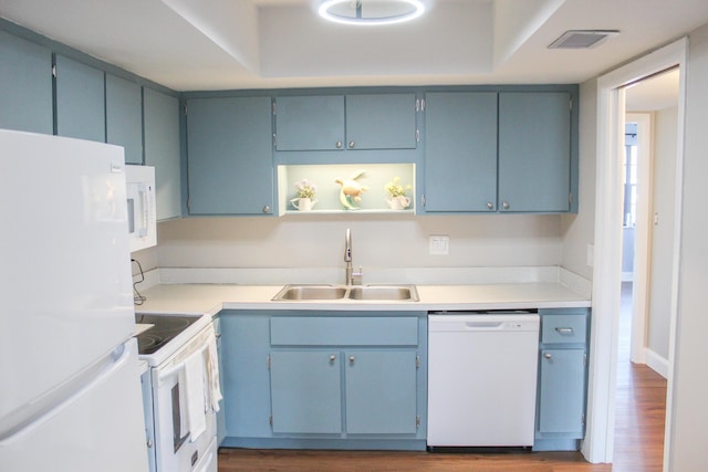 kitchen with white appliances, dark wood-style flooring, a sink, visible vents, and light countertops