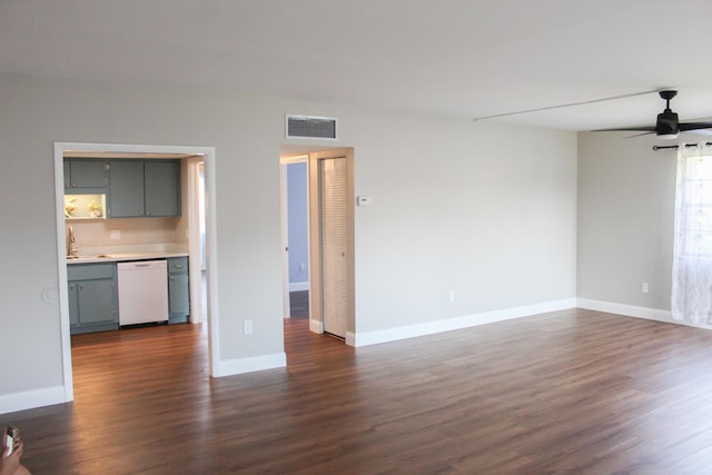 unfurnished living room with dark wood-type flooring, a sink, visible vents, baseboards, and a ceiling fan