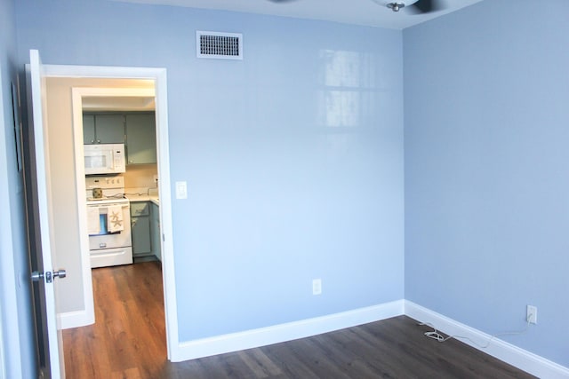 empty room with baseboards, visible vents, and dark wood finished floors