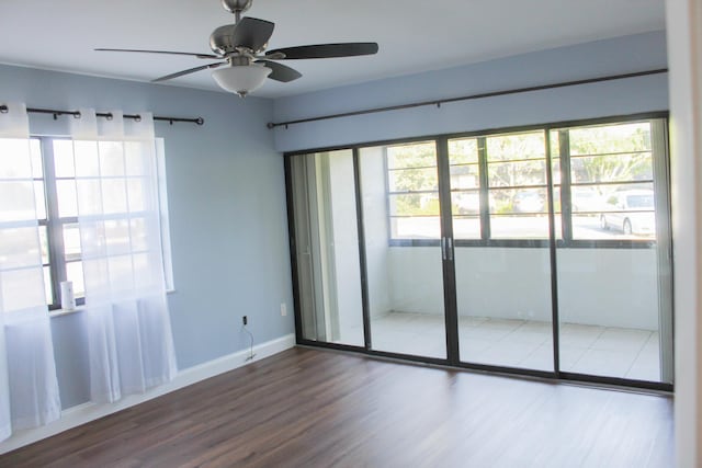 spare room featuring a wealth of natural light, ceiling fan, baseboards, and wood finished floors