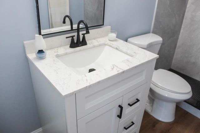 half bath featuring vanity, toilet, and wood finished floors