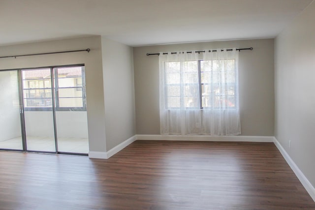 spare room featuring baseboards, wood finished floors, and a healthy amount of sunlight