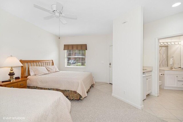 bedroom featuring ensuite bathroom, ceiling fan, light tile patterned floors, and baseboards