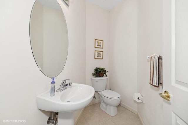 bathroom featuring toilet, baseboards, a sink, and tile patterned floors