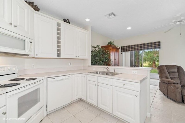 kitchen featuring a peninsula, white appliances, a sink, visible vents, and light countertops