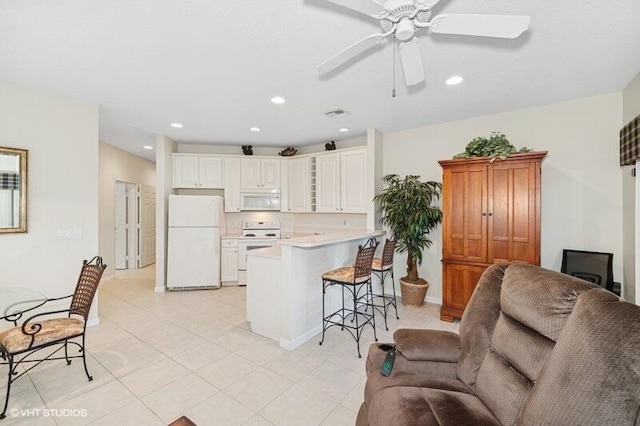 kitchen featuring white appliances, a breakfast bar area, open floor plan, a peninsula, and light countertops