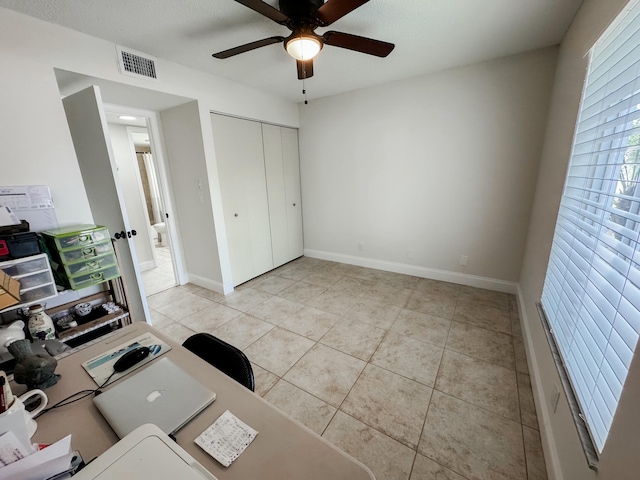 unfurnished office with light tile patterned flooring, ceiling fan, visible vents, and baseboards