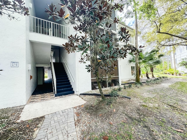 view of side of home featuring stairs and stucco siding