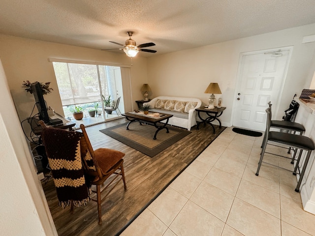 living room with light wood-style floors, ceiling fan, and a textured ceiling