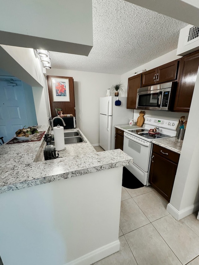 kitchen featuring dark brown cabinets, white appliances, a sink, and light countertops