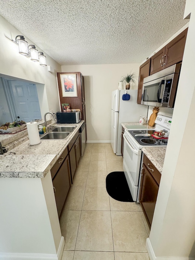 kitchen with white appliances, light tile patterned floors, a peninsula, light countertops, and a sink