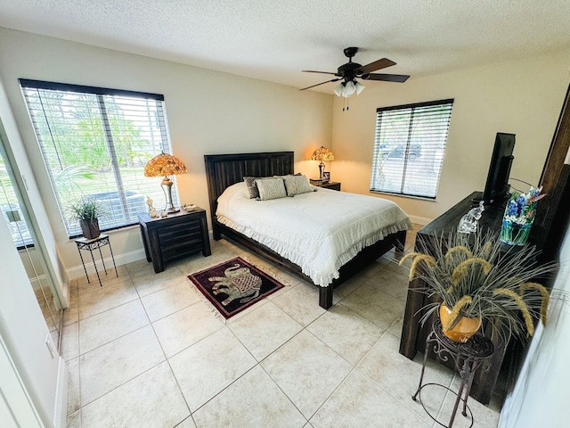 bedroom featuring a ceiling fan, light tile patterned flooring, a textured ceiling, and baseboards