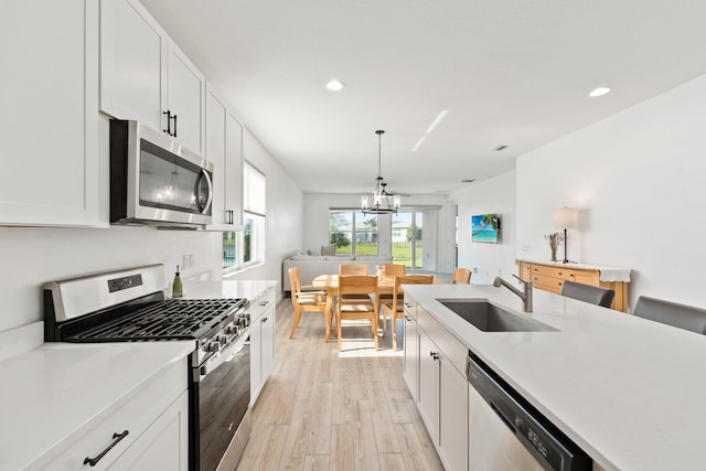 kitchen with stainless steel appliances, light countertops, a sink, and light wood-style flooring